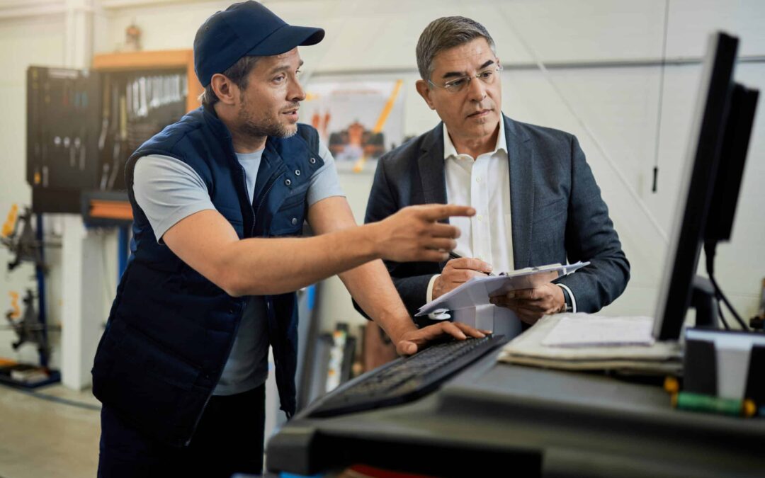 Auto repairman and manager cooperating while using computer in a